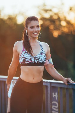 Çalışan ve açık havada Şehir Köprüsü'nde germe güzel atletik bir kadın. Günbatımı renkleri