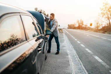 Araba arızası ya da motor arızası. Zarif orta yaşlı adam yolda araba kazası için çekici servisi bekliyor. Yol kenarı yardım kavramı.