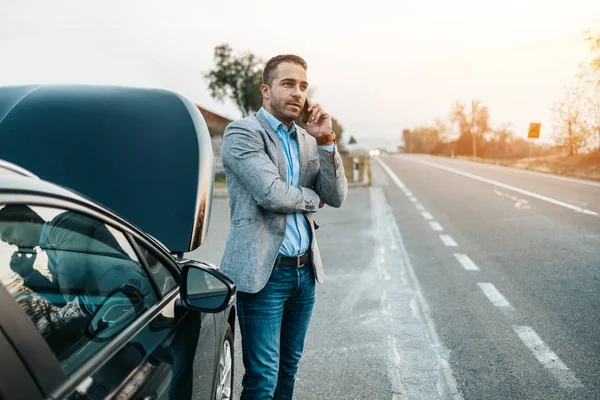 Zarif bir orta yaşlı iş adamı yolda yardım için çekici servisini arıyor. Yol kenarı yardım kavramı.