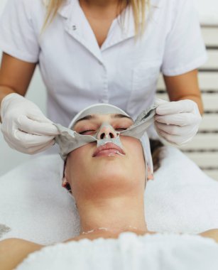 Güzel ve çekici yetişkin kadın profesyonel yüz bakımı görüyor.