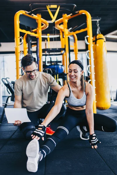 Young fit and attractive man and woman exercising workout with kettlebell in modern fitness gym.