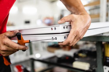 Elle çalışan işçi PVC kapı ve pencereleri birleştiriyor. İmalat işleri. Seçici odaklanma. Alüminyum ve PVC pencere ve kapı üretim fabrikası.