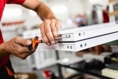 Elle çalışan işçi PVC kapı ve pencereleri birleştiriyor. İmalat işleri. Seçici odaklanma. Alüminyum ve PVC pencere ve kapı üretim fabrikası.