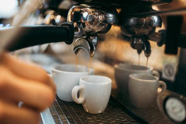 Deneyimli barmen ya da barmen ellerinin makinede lezzetli ve taze espresso kahve yaparken yakın plan çekimi..