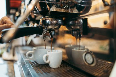 Deneyimli barmen ya da barmen ellerinin makinede lezzetli ve taze espresso kahve yaparken yakın plan çekimi..