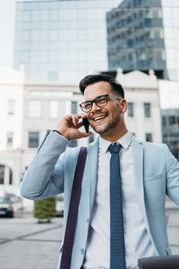 Genç modern adam akıllı telefon kullanıyor ve şehir caddesinde elektrikli scooter kullanıyor. Modern ve ekolojik ulaşım kavramı.