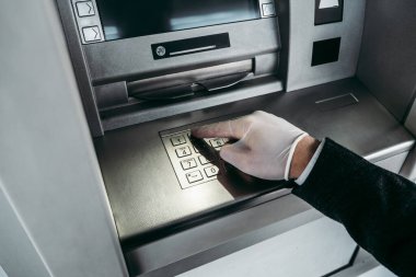 Sokak ATM 'si kullanan koruyucu maskeli ve eldivenli bir iş adamı. Virüs salgını ya da salgın hastalık konsepti. Yakın çekim..