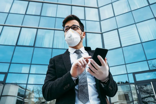 Business man with protective face mask using phone on city street. Virus pandemic or epidemic concept.