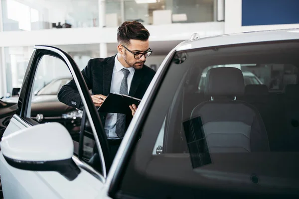 Car seller working in showroom and quality control checking of car details for the last time before buyer comes.