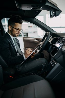 Galeride çalışan araba satıcısı ve araba detaylarını son kez kontrol ediyor alıcı gelmeden önce..