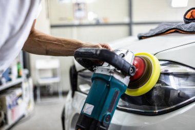 Araba tamiri, oto tamirhanesinde orbital parlatıcıyla el işi. Seçici odak.