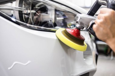 Araba tamiri, oto tamirhanesinde orbital parlatıcıyla el işi. Seçici odak.