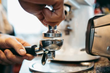 Profesyonel barmenin özel bir kafe veya kafeteryada espresso kahvesi hazırlarken yakın plan çekimi. Kahve değirmeni mi yoksa öğütücü mü kullanıyor?.