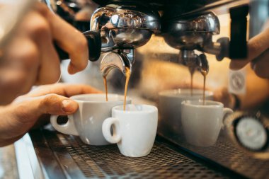 Deneyimli barmen ya da barmen ellerinin makinede lezzetli ve taze espresso kahve yaparken yakın plan çekimi..