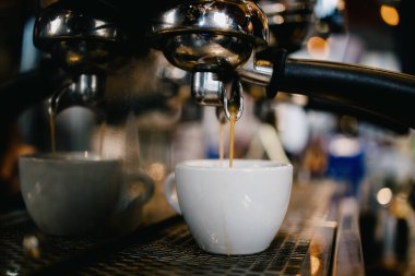 Kahve makinesini yakından çek. Lezzetli, taze ve sıcak kahveyi beyaz fincana dök..