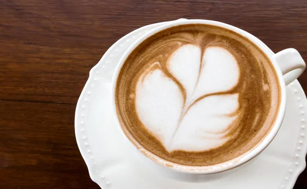 Zbliżenie filiżankę gorącej kawy tulip latte art na stół z drewna — Zdjęcie stockowe