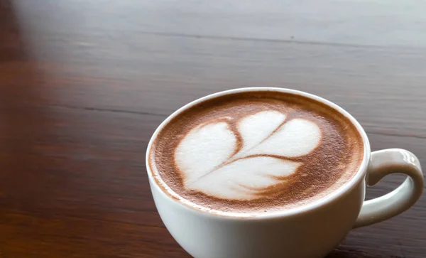 Zbliżenie filiżankę gorącej kawy tulip latte art na stół z drewna — Zdjęcie stockowe