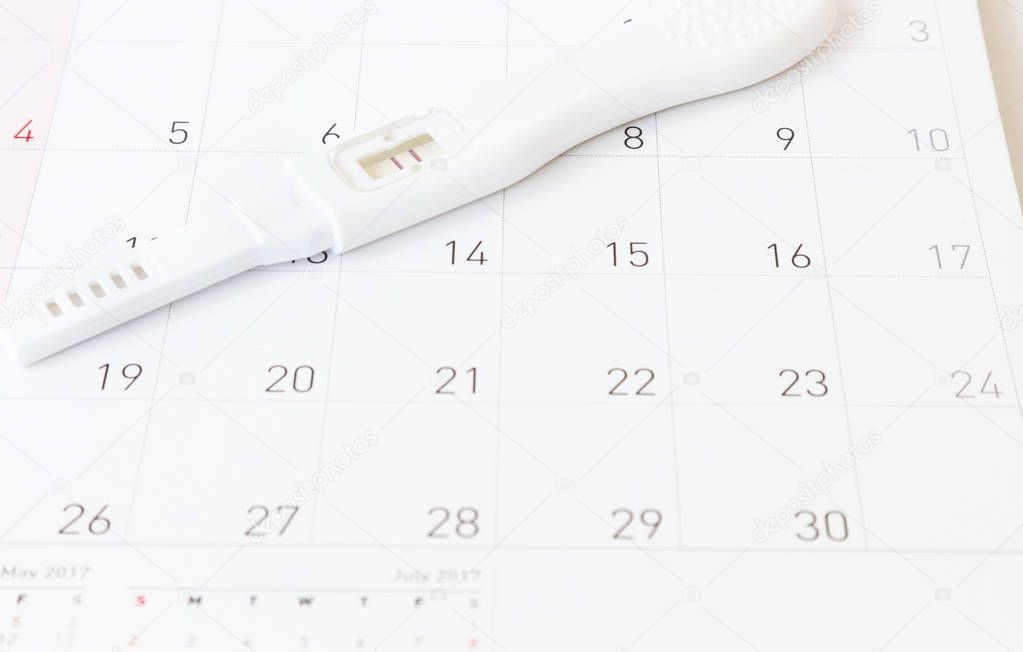 Pregnancy test on calendar background, health care concept