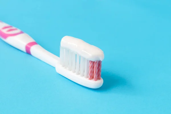 Pasta de dientes de primer plano con cepillo de dientes sobre fondo azul — Foto de Stock