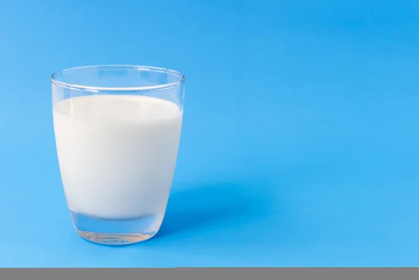 Egy pohár tej kék alapon, étel és ital az egészséges koncepcióért — Stock Fotó