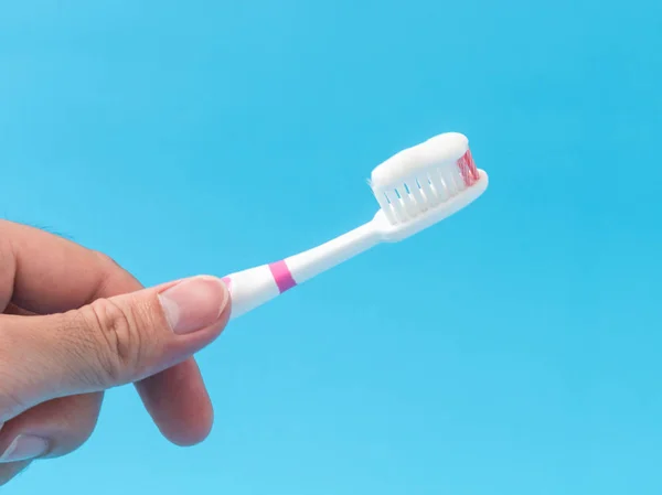 Primer plano hombre mano sosteniendo cepillo de dientes con fondo azul — Foto de Stock