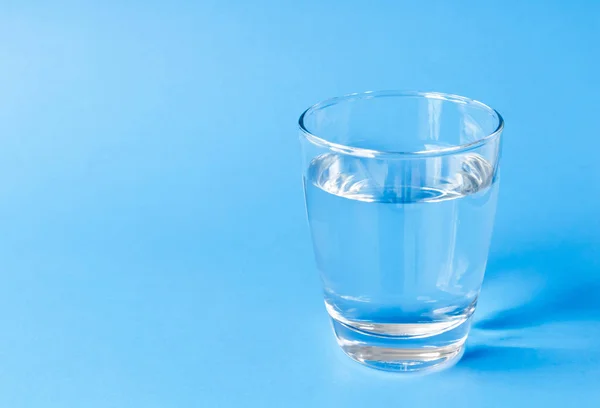 Вода в стекле на синем фоне — стоковое фото