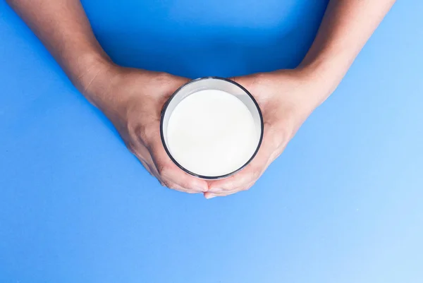 Hand met glas melk op blauwe achtergrond, eten en drinken voor gezonde concept — Stockfoto