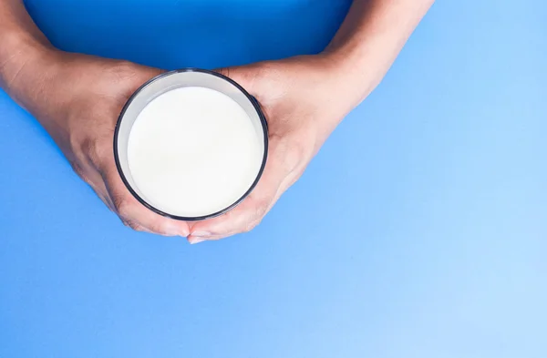 Hand met glas melk op blauwe achtergrond, eten en drinken voor gezonde concept — Stockfoto