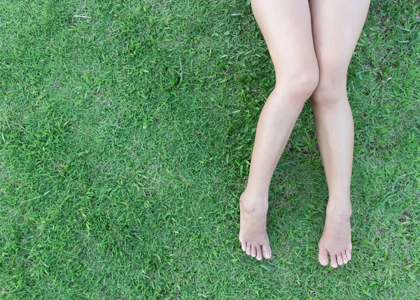 Vértes nő lába a fű háttér — Stock Fotó
