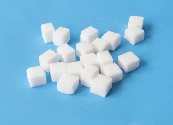 Cubos de açúcar no fundo azul, conceito de alimentos e cuidados de saúde, foco seletivo — Fotografia de Stock