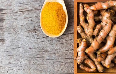 Closeup üstten görünüm zerdeçal tozu ve zerdeçal kökleri eski ahşap arka plan, spa güzellik cilt bakım kavramı üzerinde