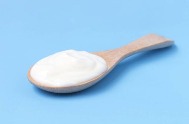 Tahta kaşık ile mavi arka plan üzerinde Yunan yoğurt