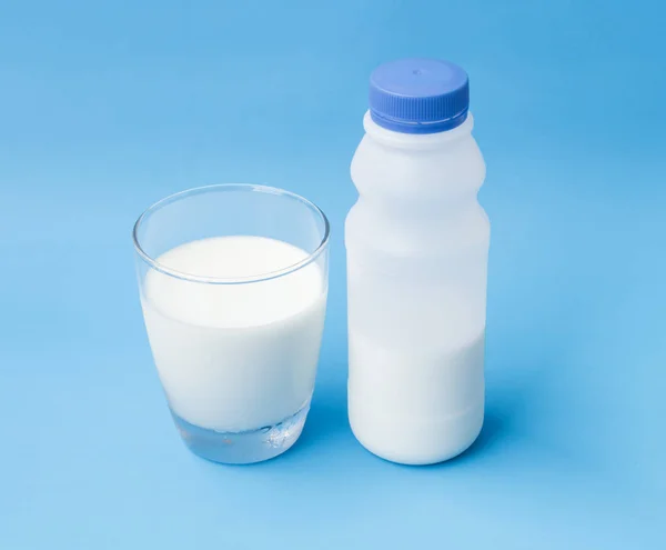 Glas und Plastikflasche Milch auf blauem Hintergrund, Essen und Trinken für ein gesundes Konzept — Stockfoto