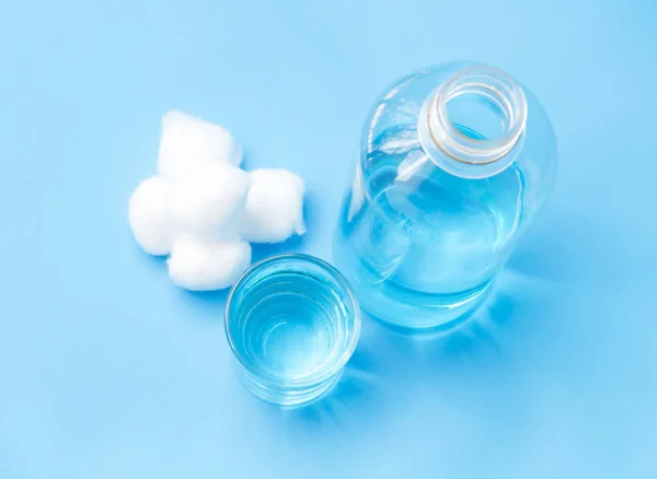 Bouteille en verre d'alcool bleu et de laine de coton sur fond bleu — Photo