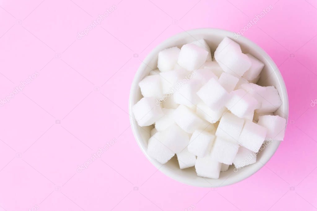 Closeup sugar cubes on bowl with pink background