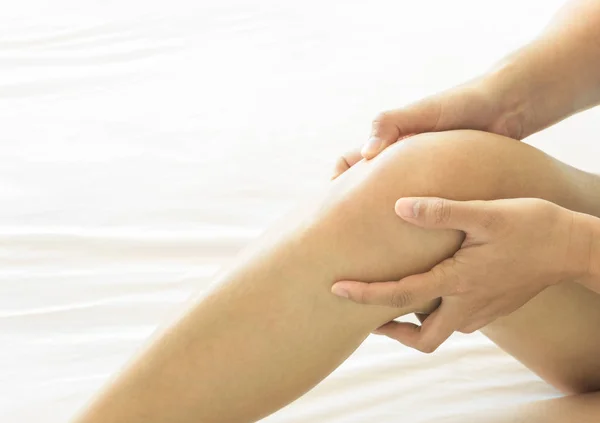 Close-up mão mulher segurando joelho com dor na cama, cuidados de saúde e conceito médico — Fotografia de Stock