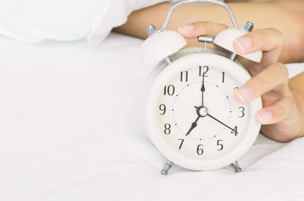 Closeup mão mulher desligar despertador na cama branca na parte da manhã para acordar conceito de tempo — Fotografia de Stock