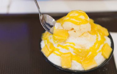 Closeup mango bingsu dondurma Kore tatlı yeme, kaşık ile mutlu hissediyor