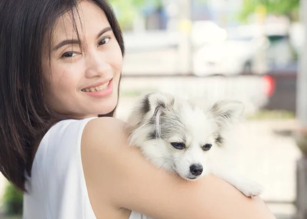 Closeup happy woman with white pomeranian dog on hand, pet health care concept with soft and selective focus — Stock Photo, Image