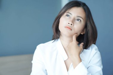 Yatak odasında yatakta oturan, düşünceli ya da depresif, seçici odaklı bir kadın.