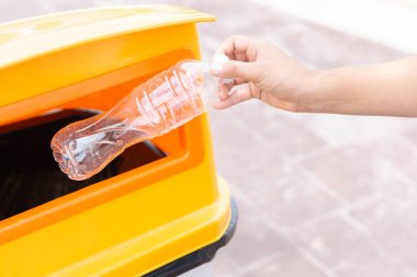 Çöp plastik şişeyi geri dönüşüm çöp kutusuna tutarak el ele kapama, seçici odak