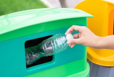 Çöp plastik şişeyi geri dönüşüm çöp kutusuna tutarak el ele kapama, seçici odak