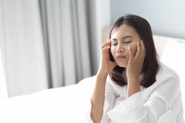 Yatak odasında yatakta oturan, düşünceli ya da depresif, seçici odaklı bir kadın.