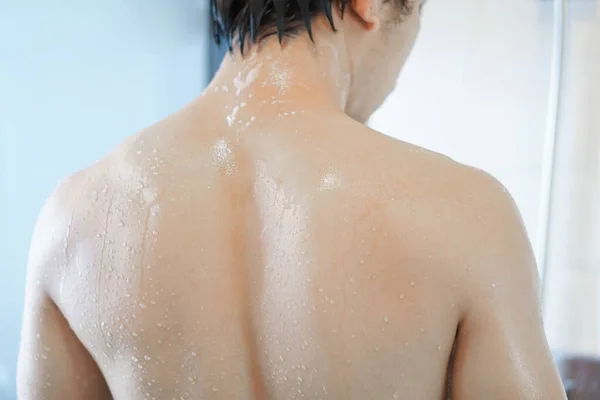 Gros plan bel homme asiatique prendre une douche dans la salle de bain, mise au point sélective — Photo