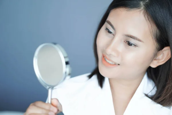 Cara cercana de la mujer mirando el espejo con sensación feliz, cuidado de la salud y concepto de belleza — Foto de Stock