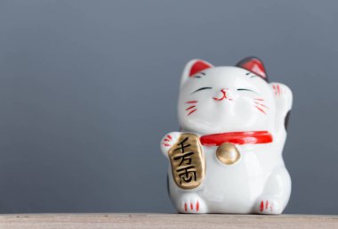 Maneki neko şanslı kedi elimizdeki metni gösterir yani ahşap masa zemininde zengindir, odak noktasını seçin