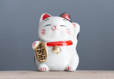 Maneki neko lucky cat show text on hand meaning rich on wood table background, select focus clipart