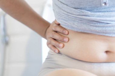 Karın yüzeyine yakın el ele tutuşan şişman kadın, sağlıklı bakım ve güzellik konsepti