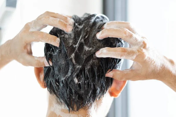 Closeup jovem homem lavar o cabelo com xampu no banheiro, tom vintage, foco seletivo — Fotografia de Stock