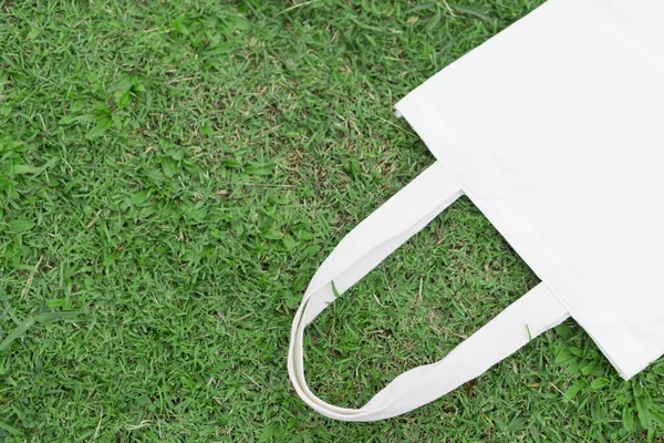 Closeup tecido de lona saco branco no fundo de grama verde, Salve o conceito de mundo — Fotografia de Stock